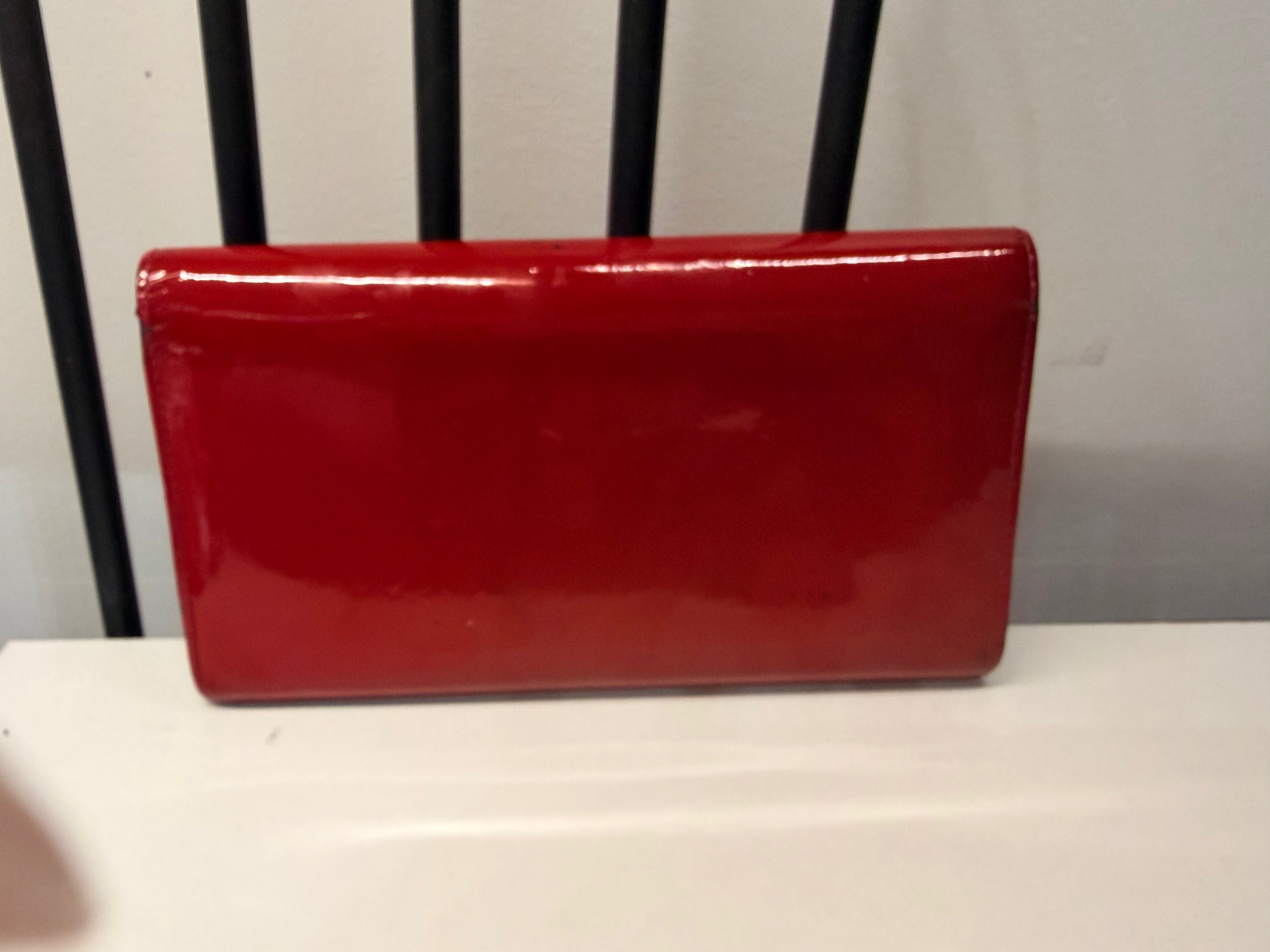 Louis Vuitton long wallet crafted in glossy red patent leather with a large gold-tone LV logo on the front.