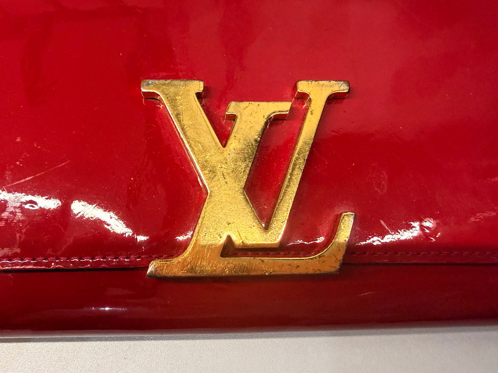 Louis Vuitton long wallet crafted in glossy red patent leather with a large gold-tone LV logo on the front.