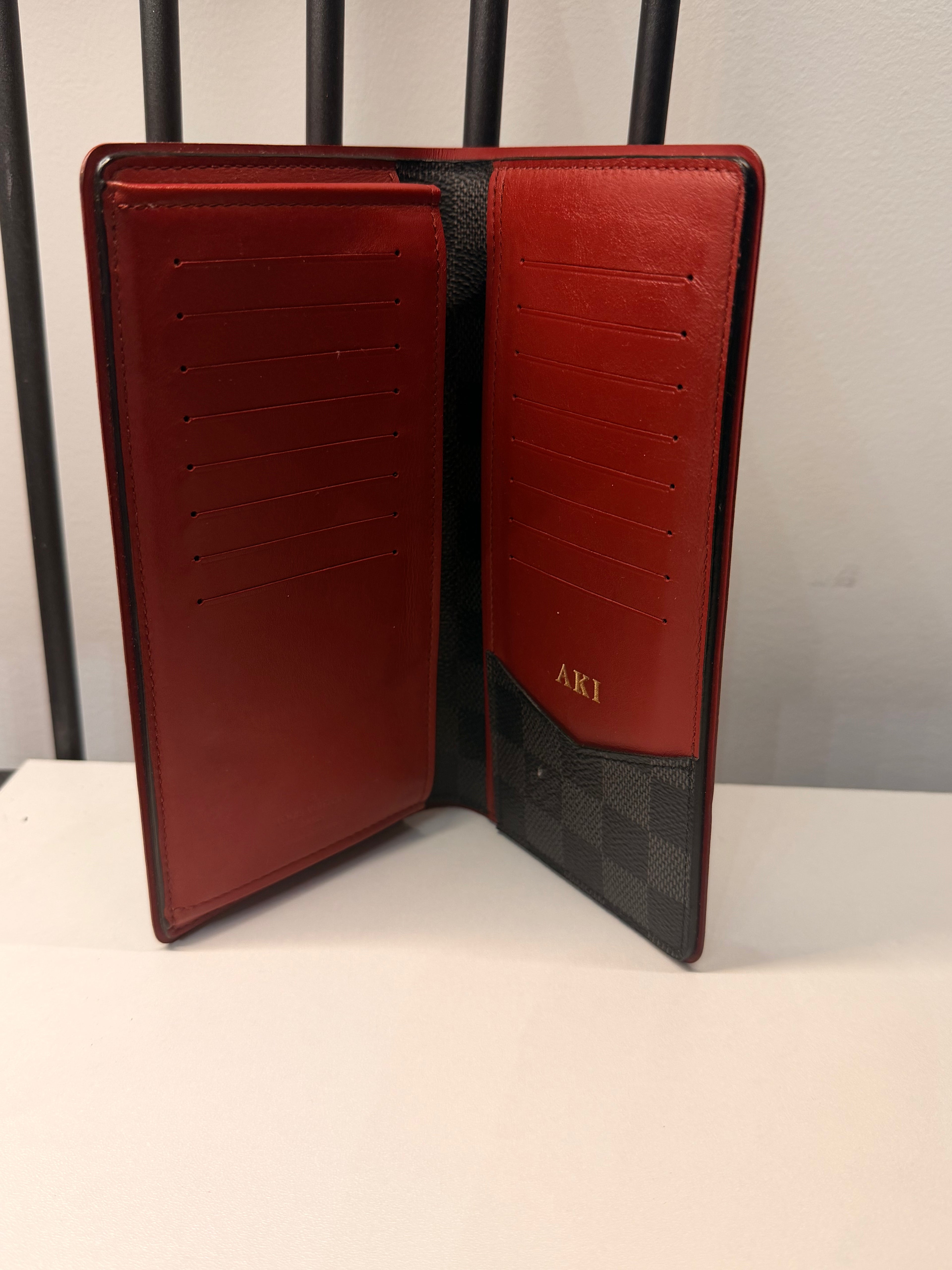 Louis Vuitton long wallet crafted in black and grey Damier Graphite coated canvas with contrasting red leather trim.