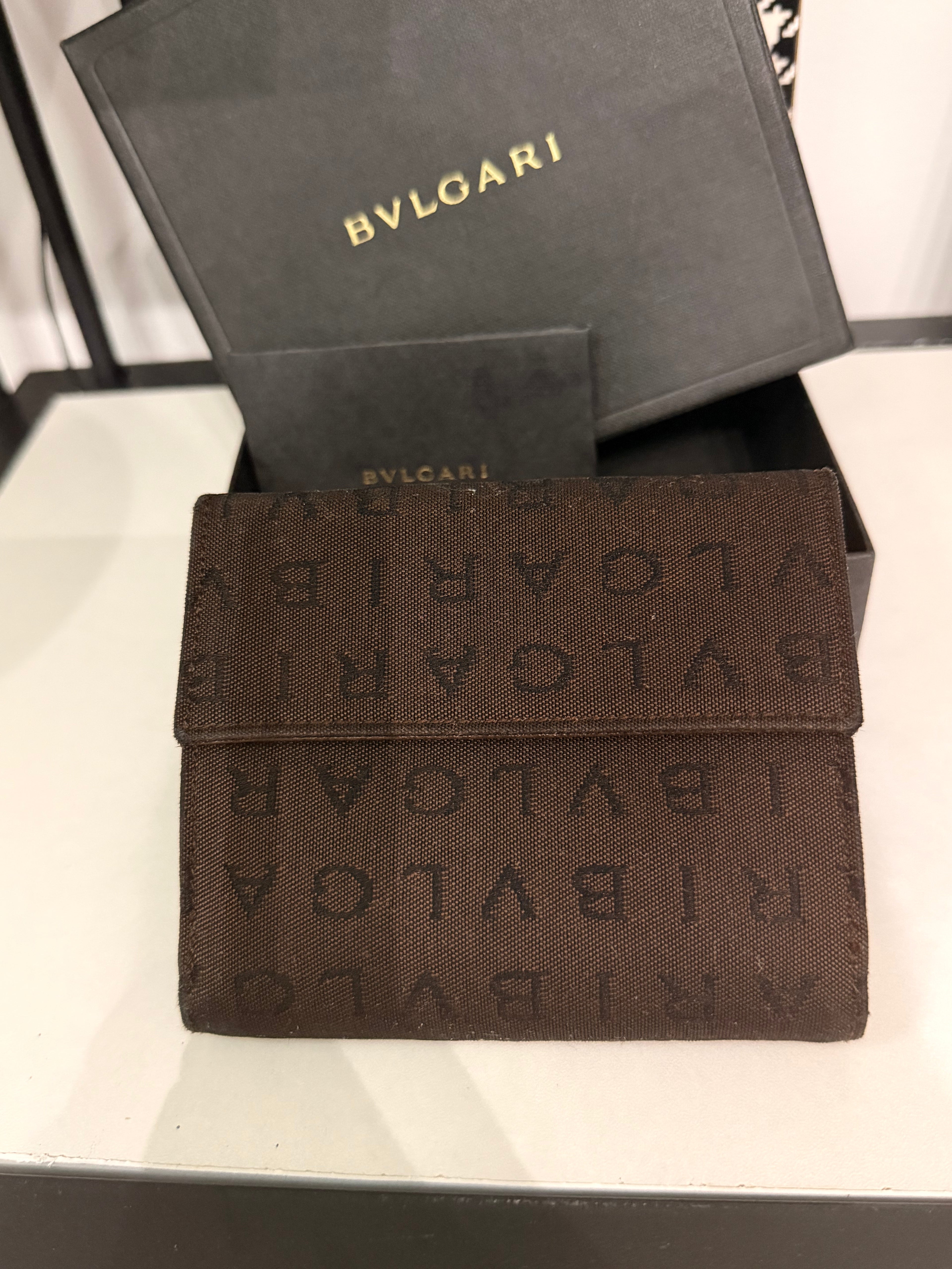 Bvlgari compact wallet featuring the signature Logo Mania monogram fabric in dark brown with matching textured leather trim.