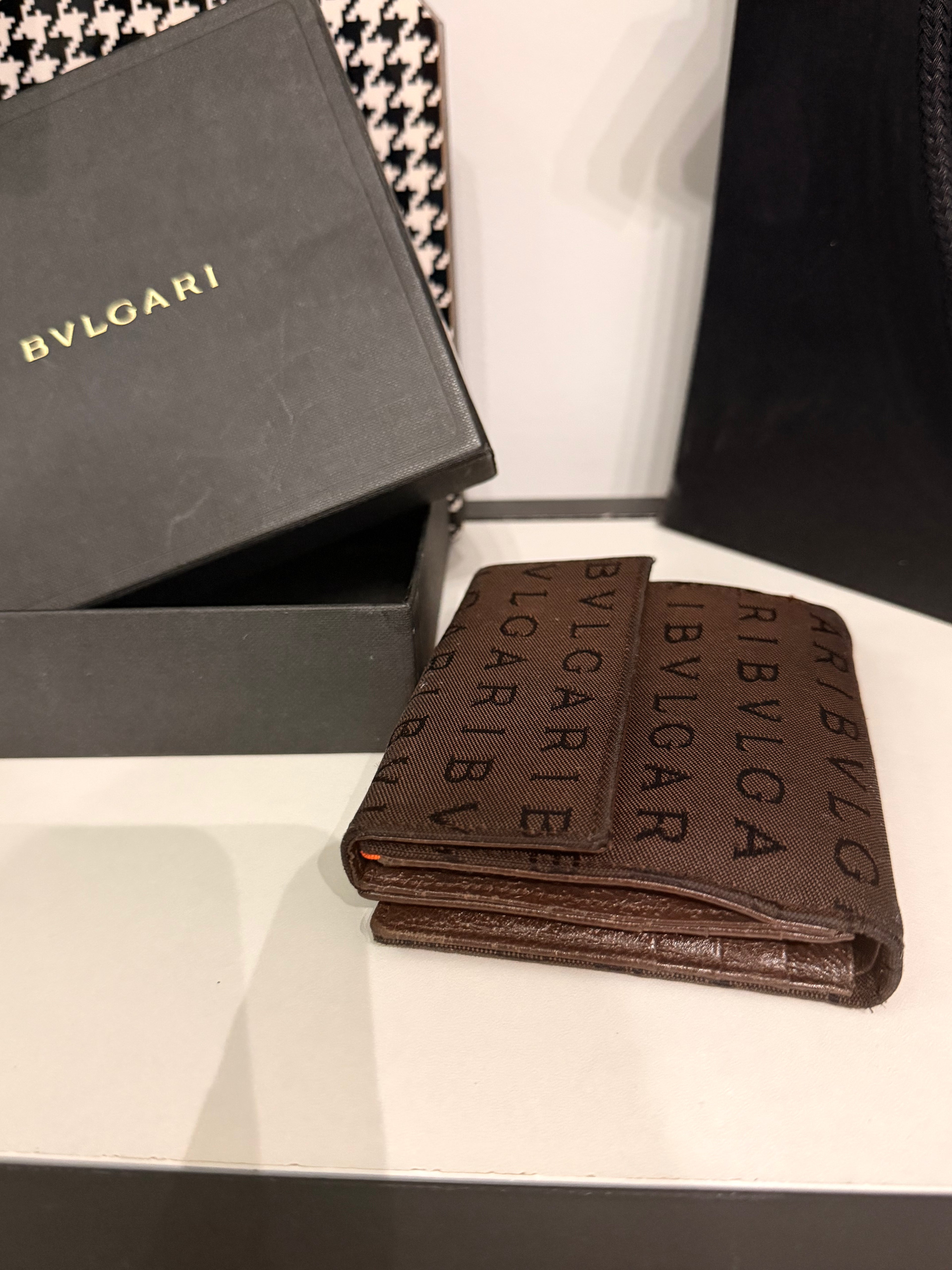 Bvlgari compact wallet featuring the signature Logo Mania monogram fabric in dark brown with matching textured leather trim.