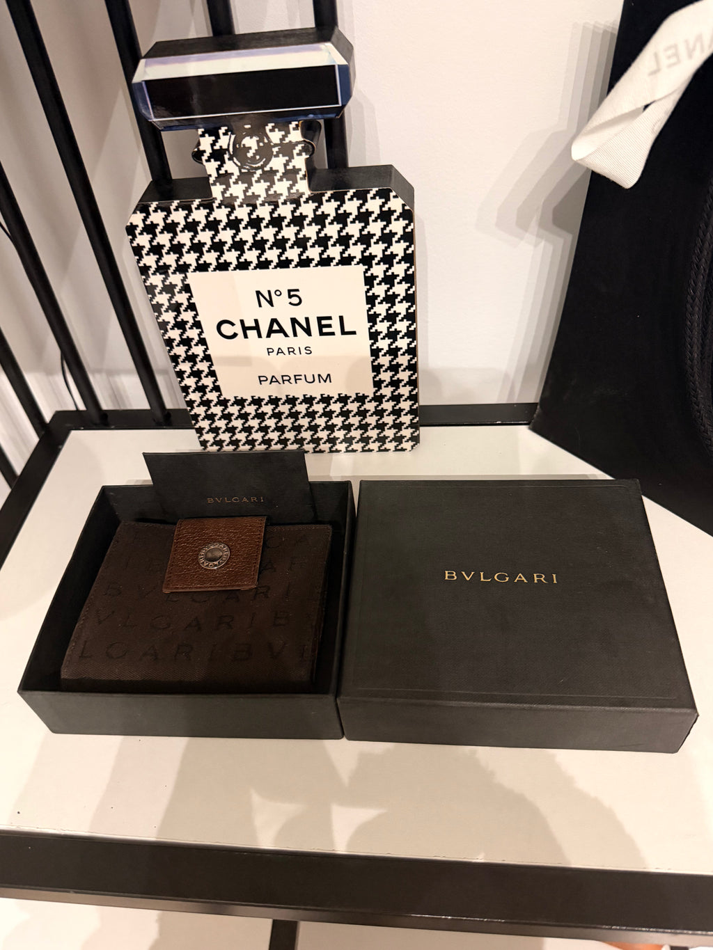 Bvlgari compact wallet featuring the signature Logo Mania monogram fabric in dark brown with matching textured leather trim.