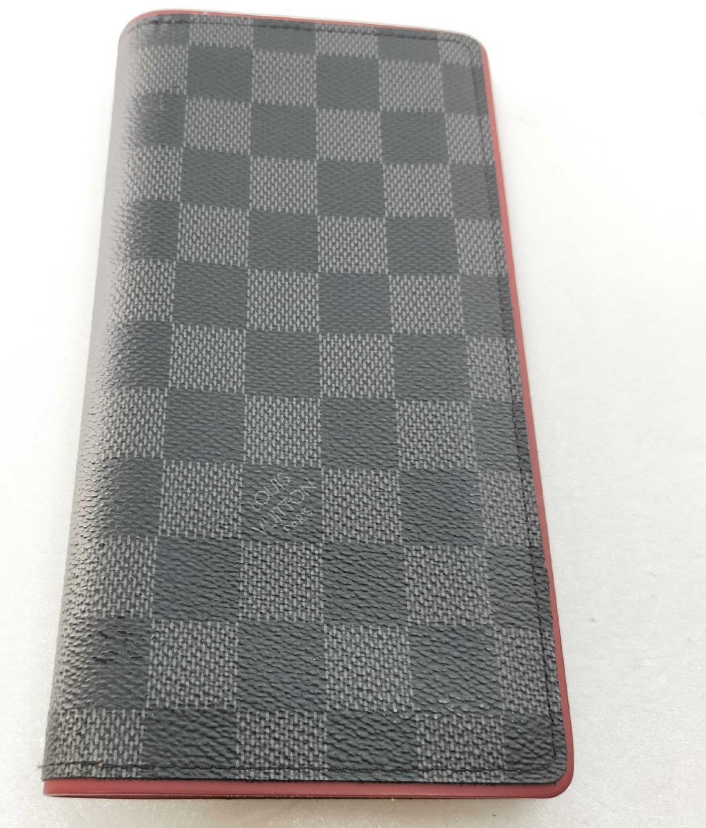 Louis Vuitton long wallet crafted in black and grey Damier Graphite coated canvas with contrasting red leather trim.