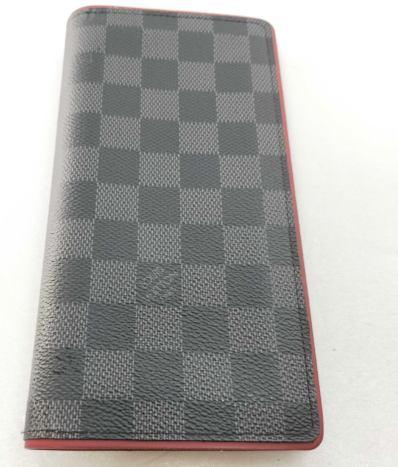 Louis Vuitton long wallet crafted in black and grey Damier Graphite coated canvas with contrasting red leather trim.