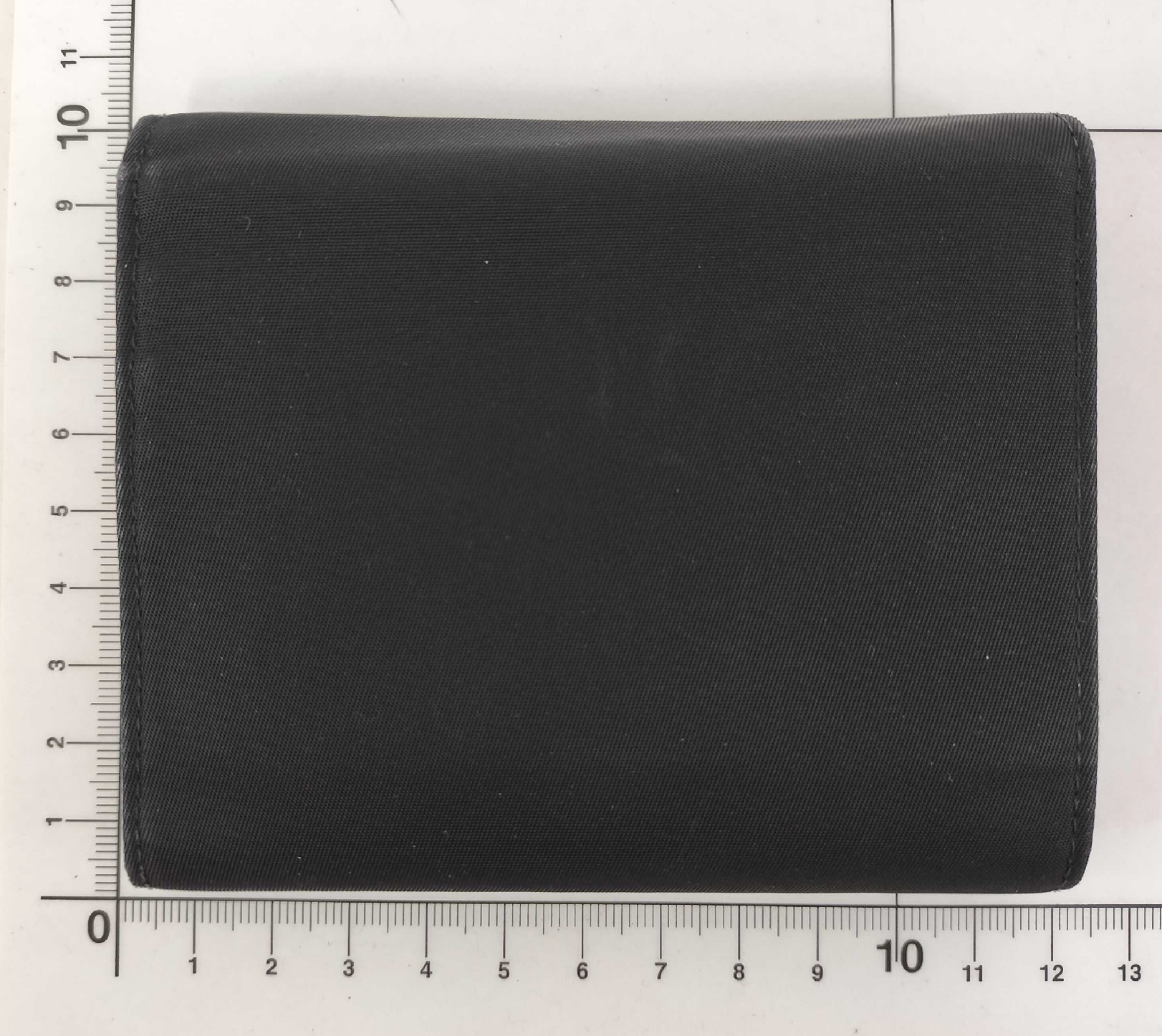 Classic Prada compact wallet crafted from durable black Tessuto nylon and finished with the iconic silver-tone triangular Prada Milano logo plaque.