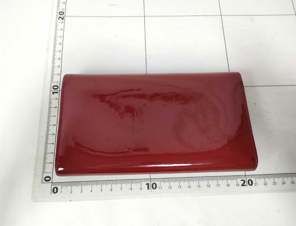 Louis Vuitton long wallet crafted in glossy red patent leather with a large gold-tone LV logo on the front.