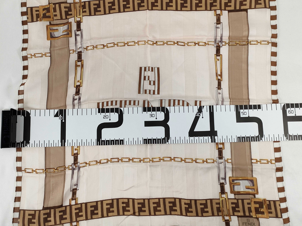 Fendi scarf featuring the iconic FF monogram, belt and chain motifs in soft beige, cream, brown, and gold tones.