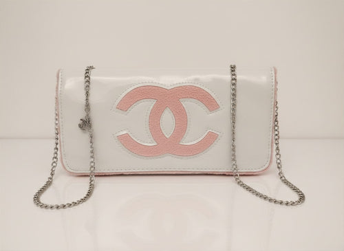 Chanel Beauty Bag features a white patent leather exterior with a prominent pink logo design