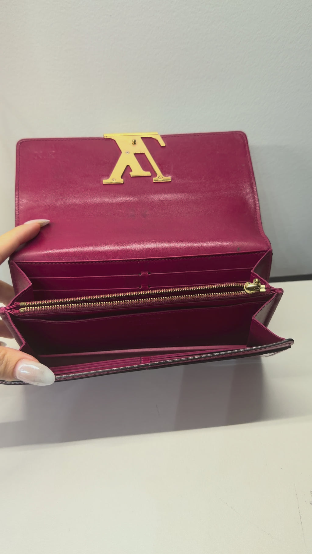 Louis Vuitton long wallet crafted in glossy red patent leather with a large gold-tone LV logo on the front.