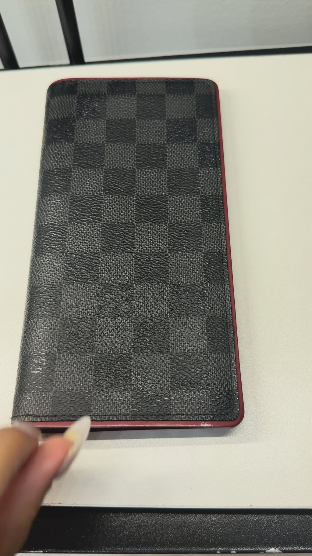 Louis Vuitton long wallet crafted in black and grey Damier Graphite coated canvas with contrasting red leather trim.