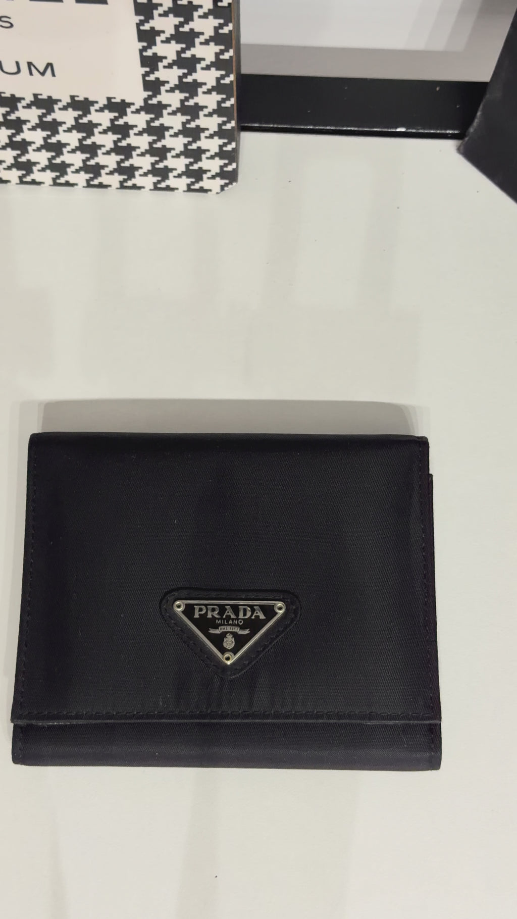Classic Prada compact wallet crafted from durable black Tessuto nylon and finished with the iconic silver-tone triangular Prada Milano logo plaque.